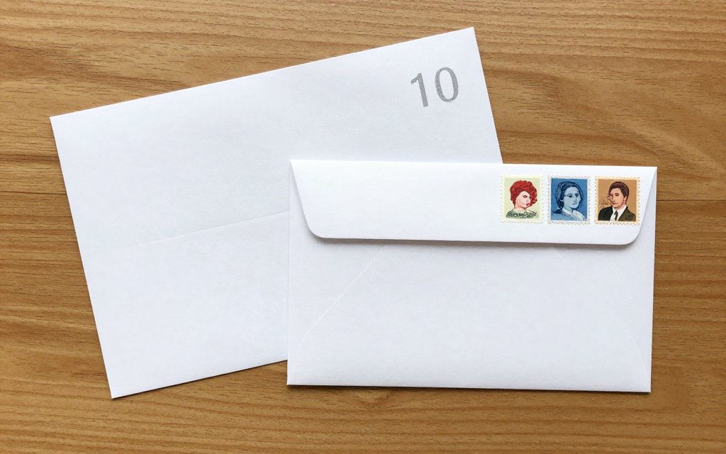 Flat lay of a letter, envelope, and postage stamps showing how many stamps to mail a letter.