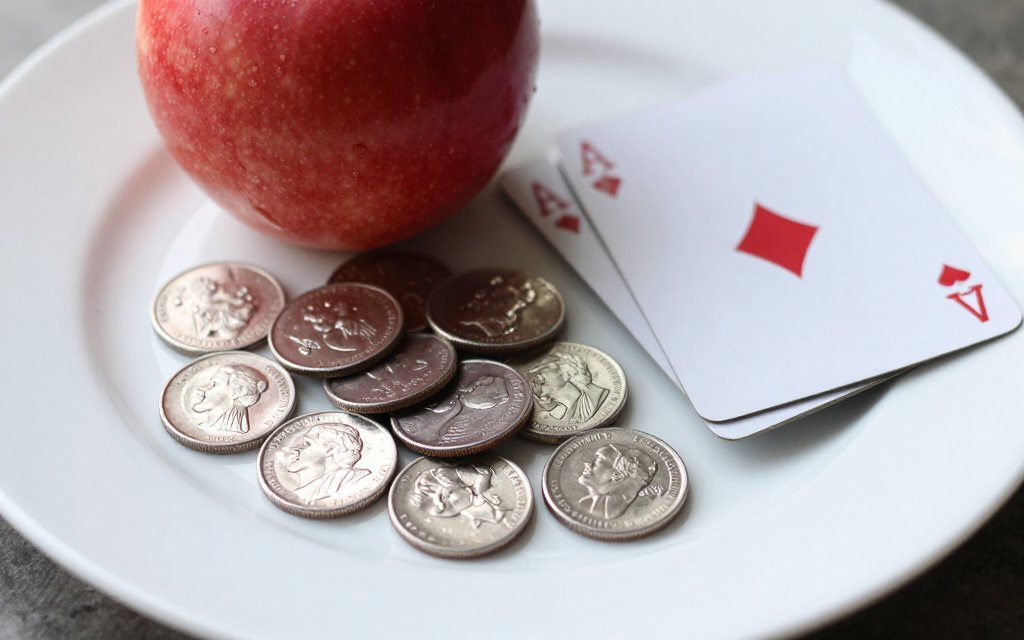 Twenty nickels, an apple, and a deck of cards showing what weighs 100 grams