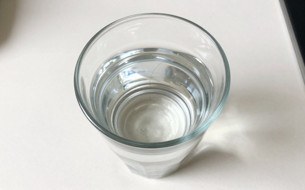 A hair porosity test with a strand floating on top of a glass of water