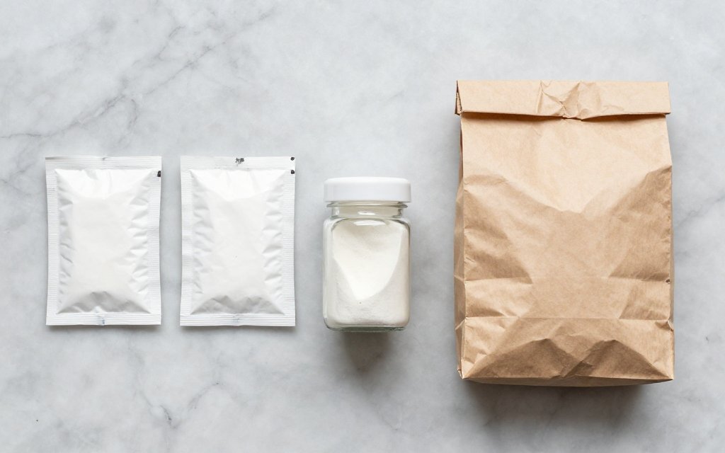 Top-down view of a strip of yeast packets, a jar and a bulk bag, comparing how much yeast in a packet versus larger packages