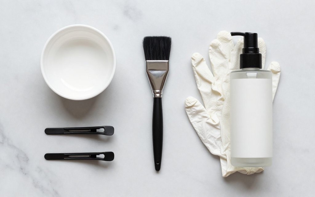 Flat-lay of tint bowl, brush and clips used for a salon gloss service